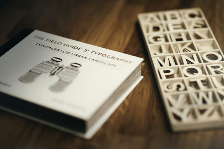 The Field Guide to Typography book placed on a wooden desk next to a wooden tray filled with alphabet letter blocks.