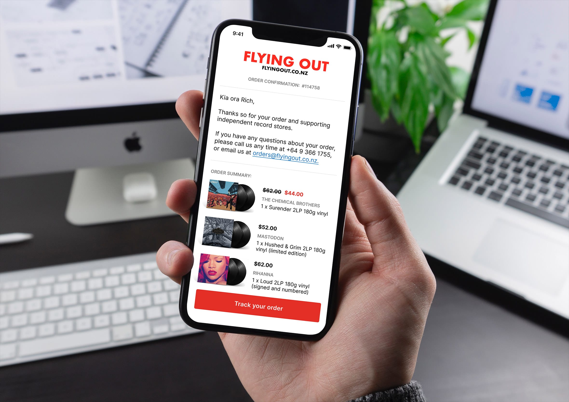 Hand holding an iPhone displaying a digital email receipt from Flying Out with itemised vinyl record purchases.