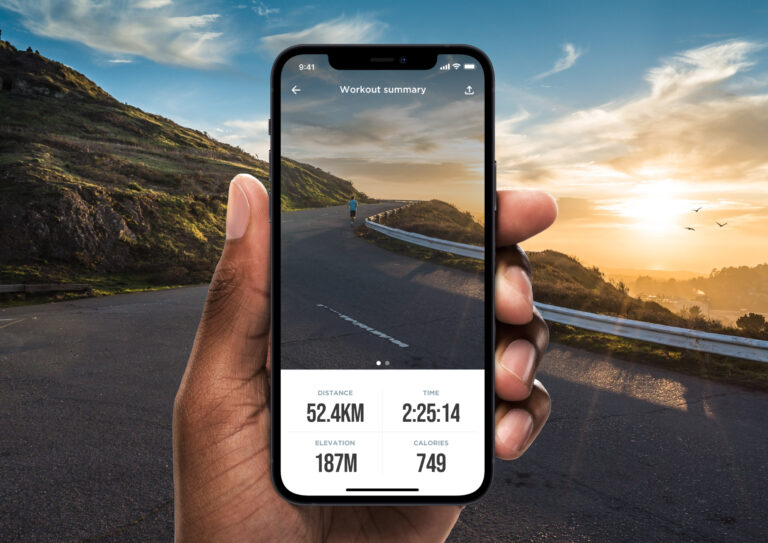 Hand holding an iPhone showing a workout summary screen with stats for distance, time, elevation, and calories.