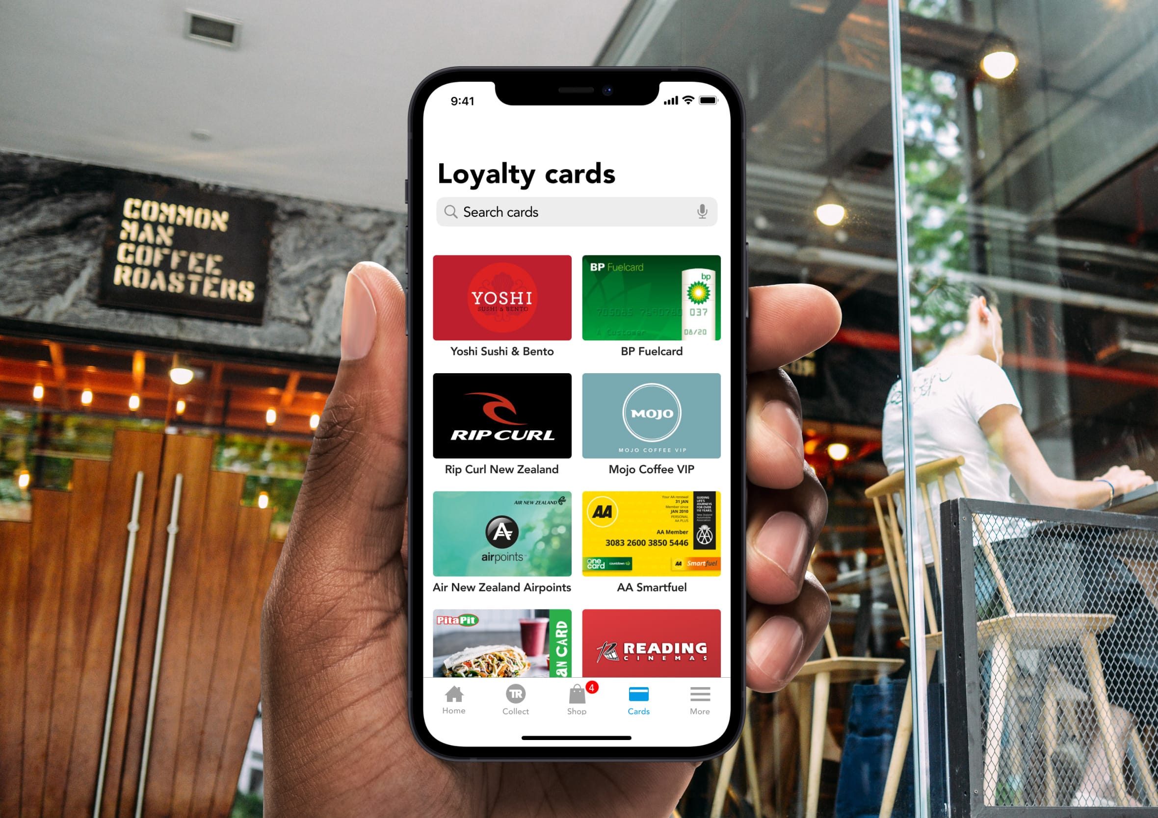 Hand holding an iPhone displaying a digital wallet app filled with store loyalty cards.