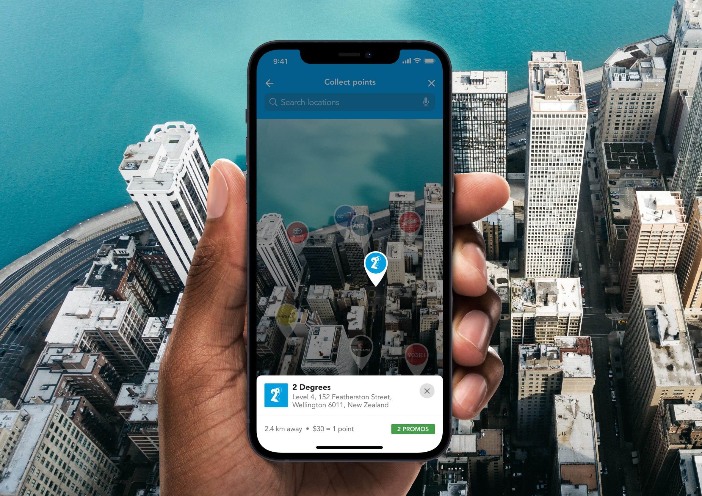 Hand holding an iPhone showing a location map app with a selected venue details card overlaid on a cityscape backdrop.