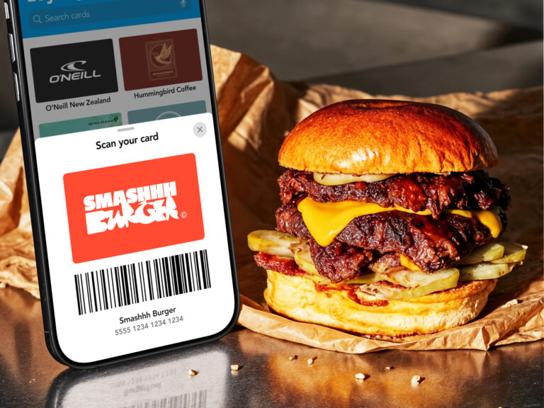 Smartphone displaying a Smashhh Burger loyalty card scan screen in a digital wallet app next to a double smash burger.