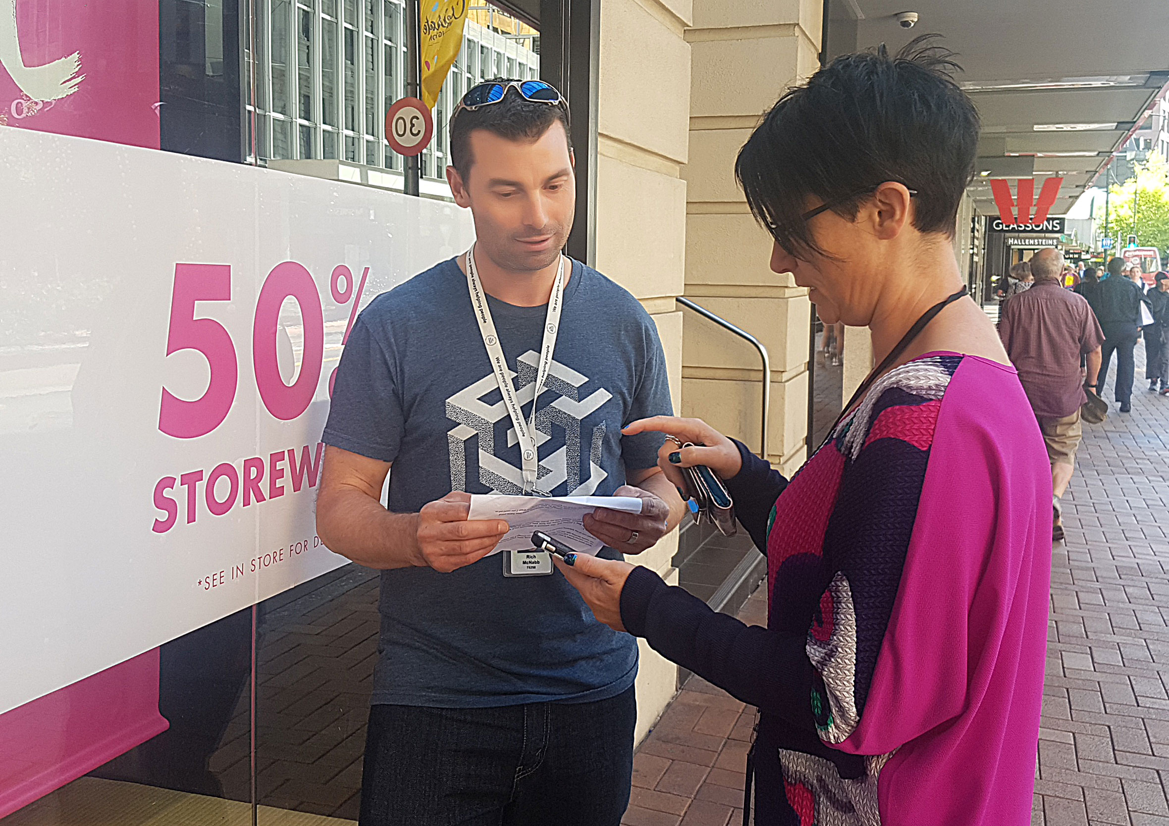 UX designer conducting guerrilla usability testing for the core banking app with a participant on a city footpath outside a shopfront.