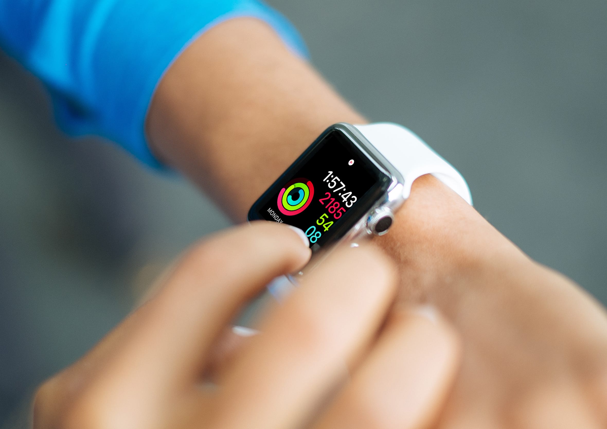 Person tapping an Apple Watch screen displaying active fitness metrics, activity rings, and workout time to track personal health data on the go.