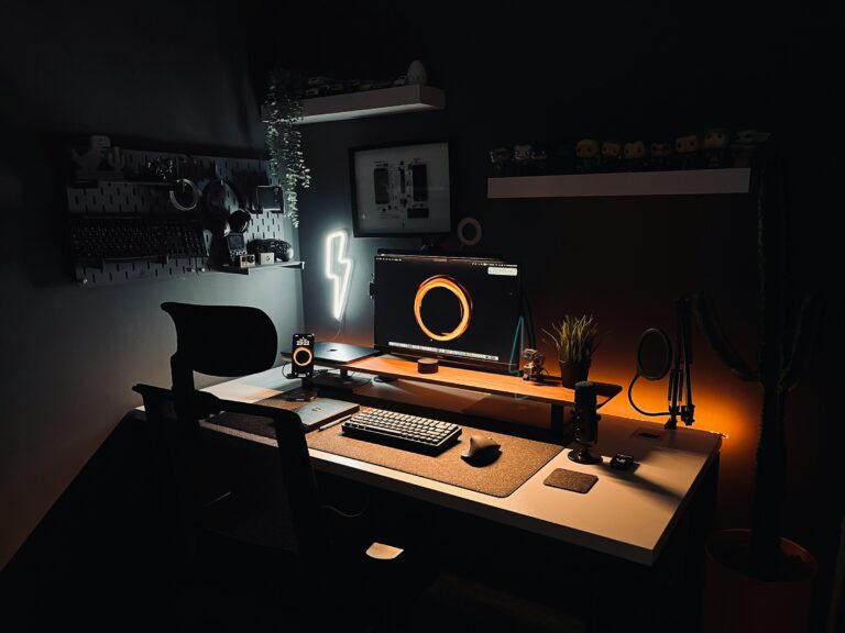 Minimalist dark computer desk setup with ambient warm backlighting, a glowing neon bolt light, and organised tech accessories for productivity.