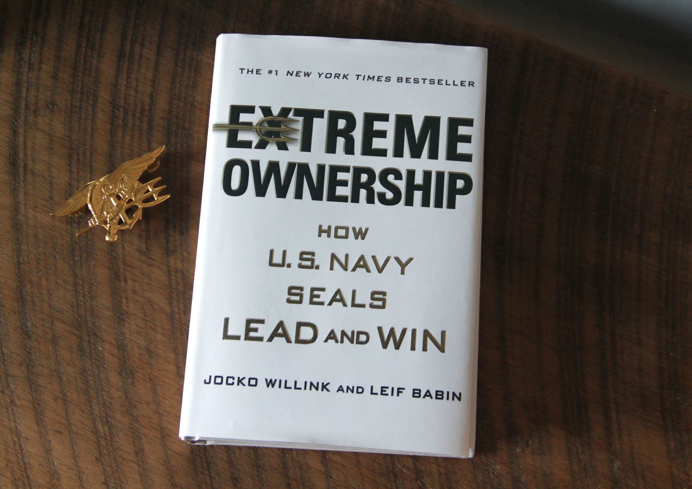 Hardcover book Extreme Ownership by Jocko Willink and Leif Babin displayed alongside a Trident insignia.