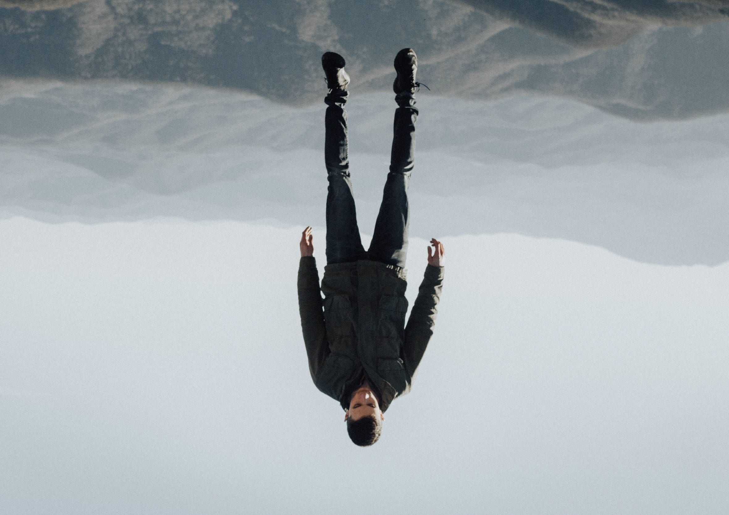 Surreal photo of a man suspended upside down against a backdrop of distant mountains