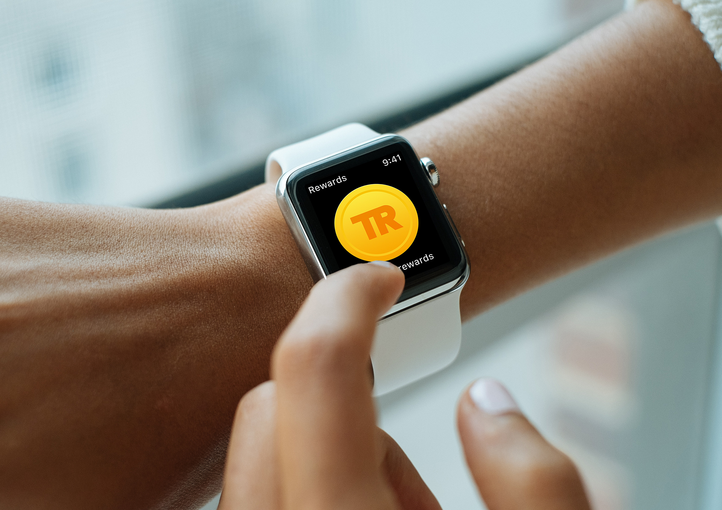 Hand tapping a smartwatch screen showing the Travel Rewards gold coin graphic interface.