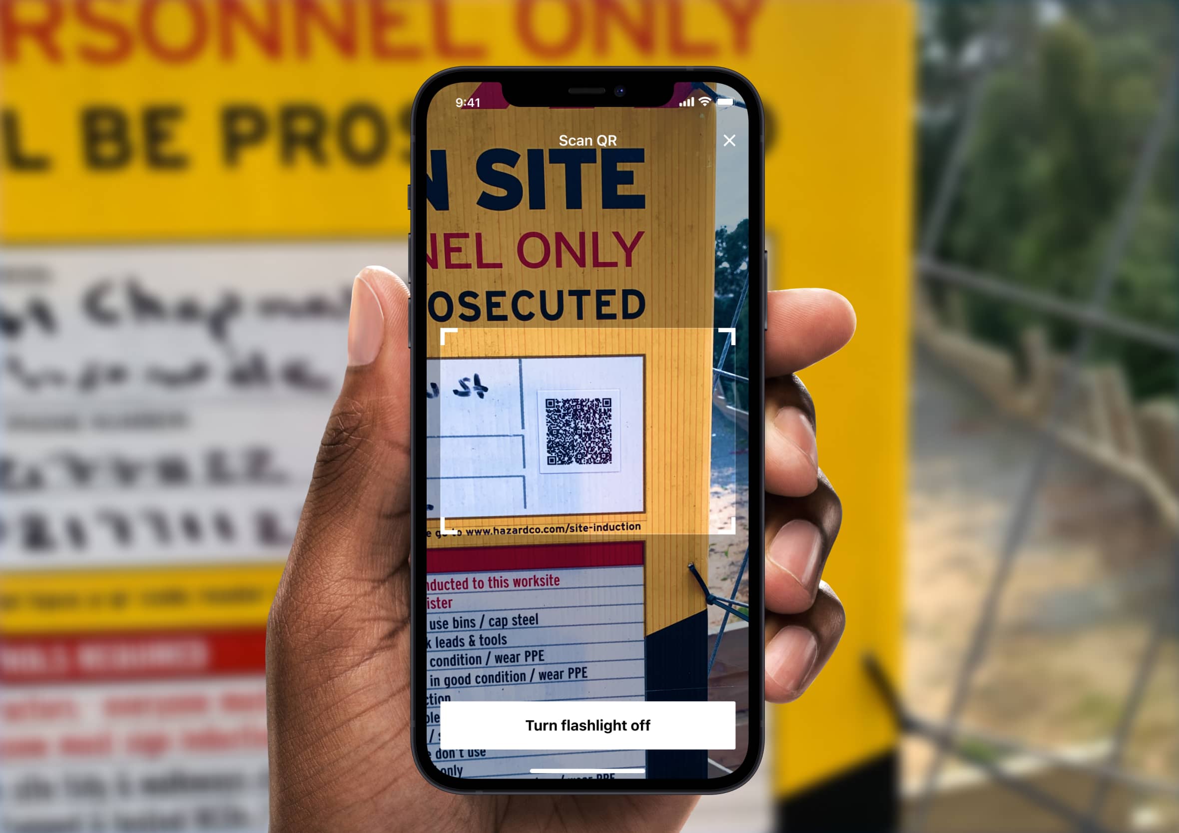 Person scanning a HazardCo QR code hazard board on a construction site