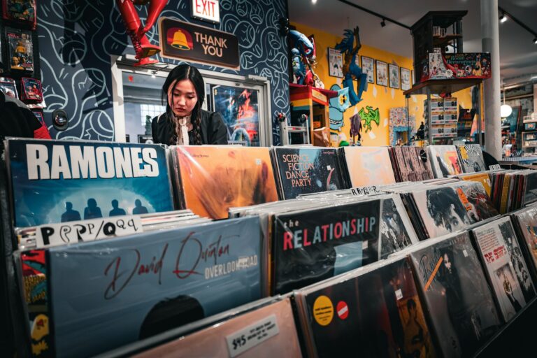 Young woman browsing through rows of classic vinyl record sleeves inside a brightly lit vintage music shop, reflecting tactile user discovery and media curation.