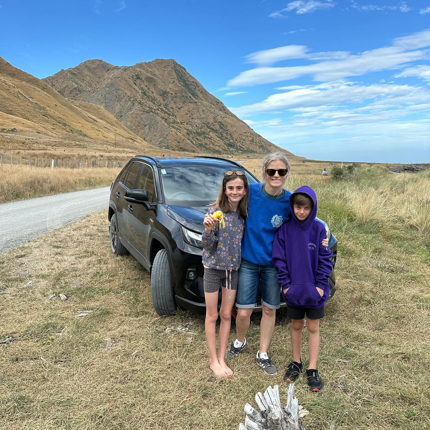Family exploring Tora in a new black SUV, joking that there's no way the old 1996 Toyota Corolla would have made the trip
