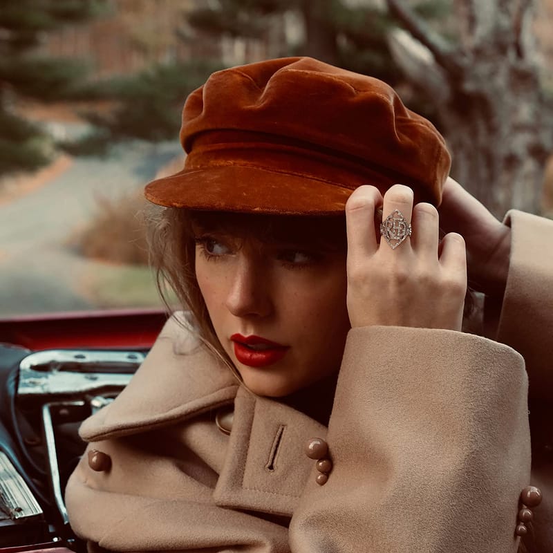 Photographic promo cover for Taylor Swift's Red (Taylor's Version), showing her wearing a velvet cap and tan coat in a vintage car.