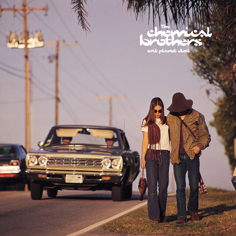 Roadside photography cover for The Chemical Brothers' Exit Planet Dust, showing two figures walking along a sunny street.