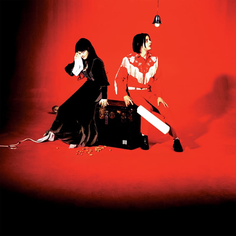 Stylized studio photo for The White Stripes' Elephant, depicting Jack and Meg White seated in a red and black room.