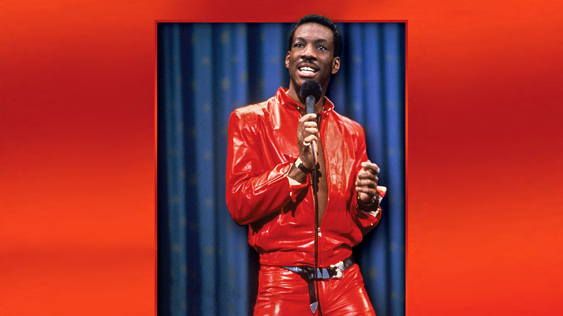 Title card for Eddie Murphy's stand-up comedy special Delirious showing Murphy in an iconic red leather suit holding a microphone.