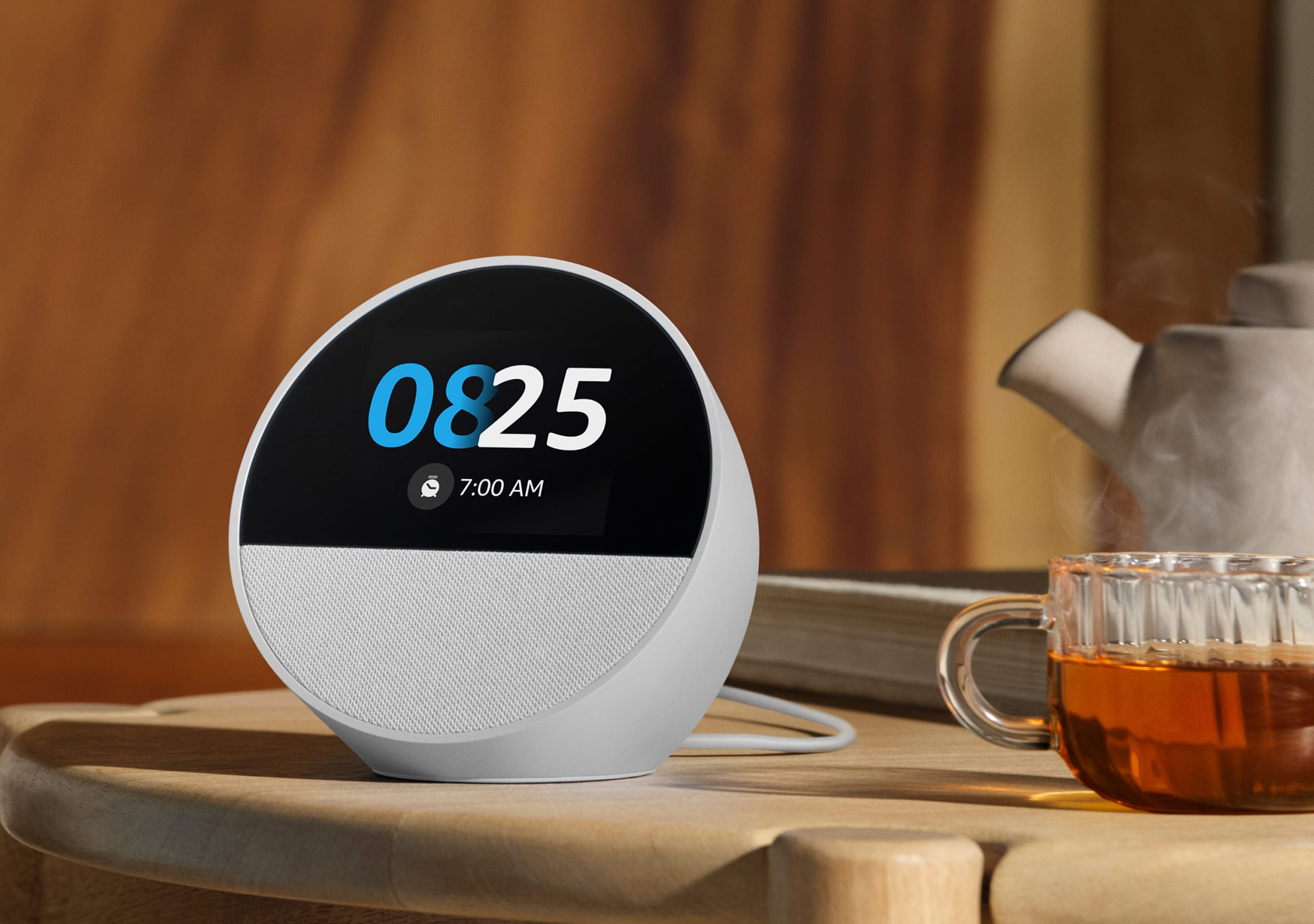 Amazon Echo Spot smart alarm clock displaying the time on a wooden bedside table