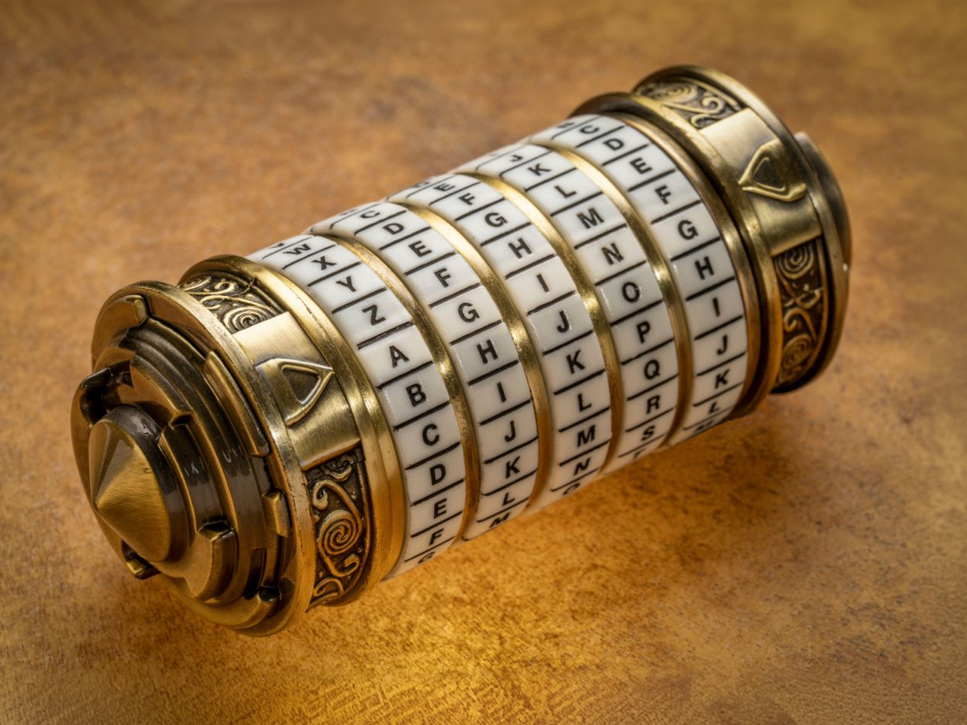 An ornate brass cryptex combination lock with rotating alphabet rings.