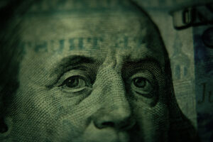 Extreme close-up of Benjamin Franklin's eyes on a US $100 bill, the fine engraving lit in warm, moody light