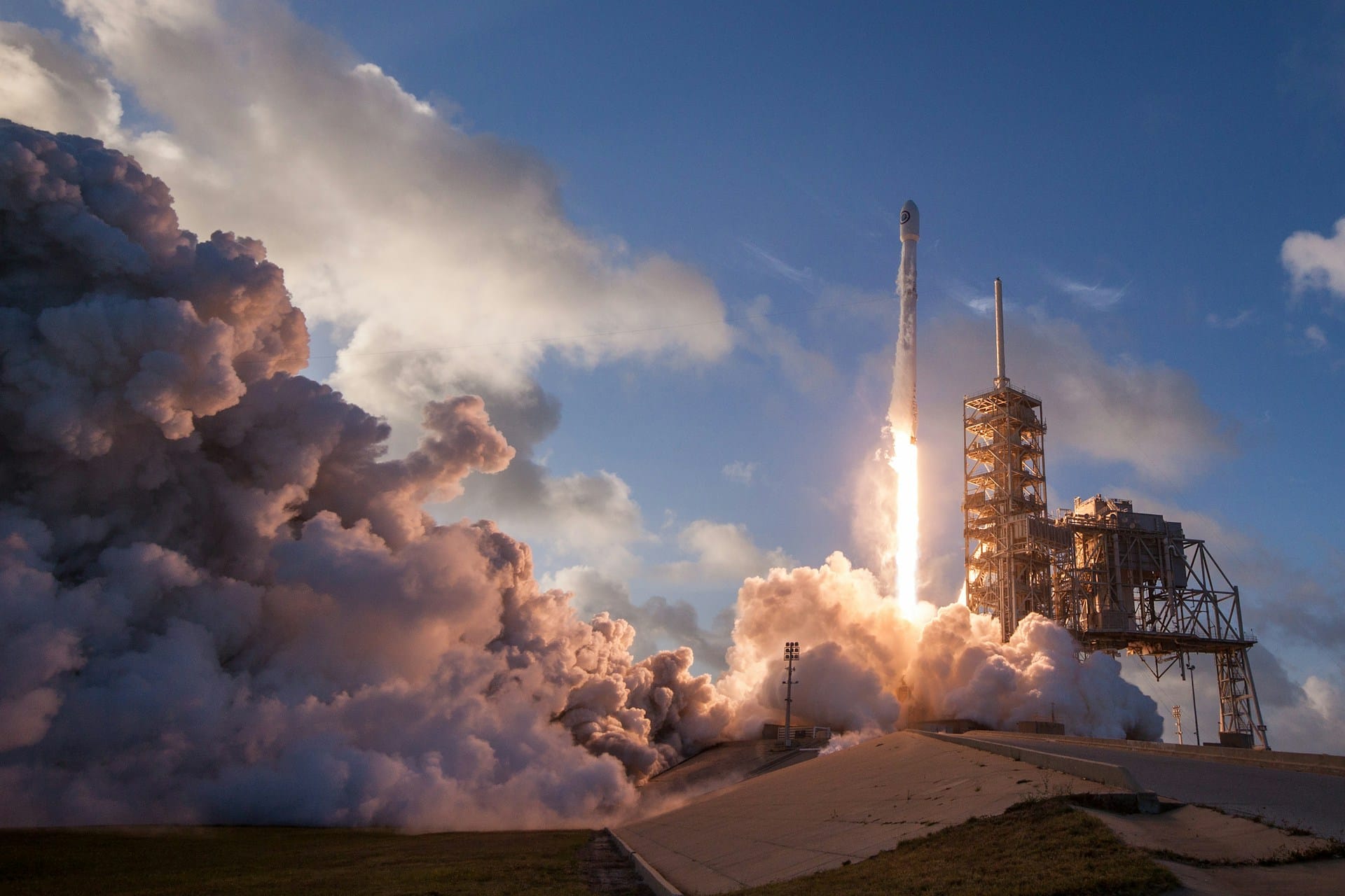 Dramatic rocket launch featuring heavy plume smoke and bright engine fire against a blue sky, showcasing high-impact technology and engineering precision for product design inspiration.
