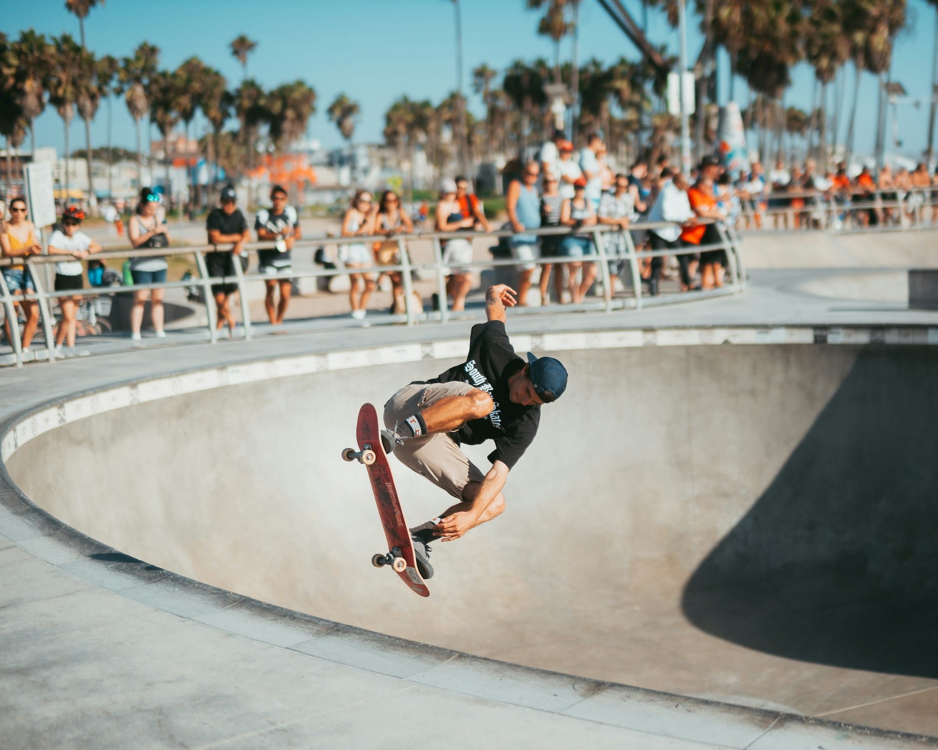 Skateboarder catching air out of a concrete skatepark bowl surrounded by palm trees and spectators, illustrating dynamic motion and creative flow for personal projects and lifestyle notes.